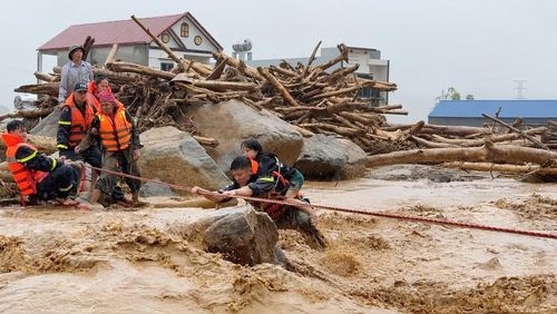 Hạ sĩ Vàng Văn Tình cõng bé gái Lò Thị Yến Thêm vượt lũ.