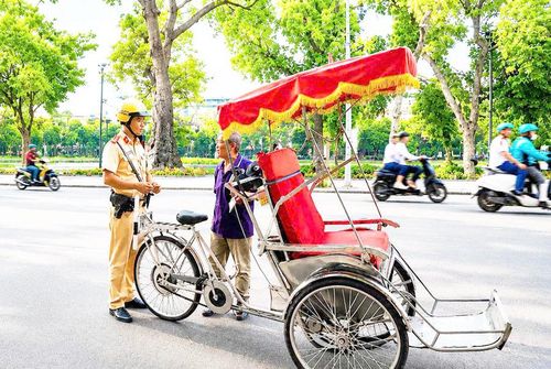 Cán bộ Đội Cảnh sát giao thông số 1, Phòng Cảnh sát giao thông (Công an thành phố Hà Nội) kiểm tra xe xích lô tại phố Đinh Tiên Hoàng (phường Hoàn Kiếm). Ảnh: Tâm Hiền