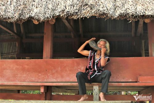 Già làng Bríu Pố thổi tù và bên nhà gươl làng Arớh, nơi ông thường truyền dạy văn hóa truyền thống cho lớp trẻ.