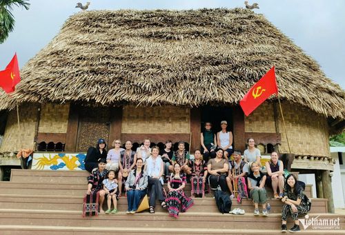 Chị Đinh Thị Thìn cùng người dân Bhơ Hôồng chụp ảnh lưu niệm với du khách trước nhà gươl của làng.