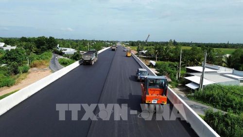 Tranh thủ thời tiết thuận lợi, đơn vị thi công tiến hành thảm nhựa cầu Kênh Xáng. Ảnh: Công Trí - TTXVN