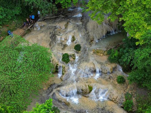 Từ xa nhìn lại, dòng thác trắng xóa uốn lượn mềm mại như dải lụa hay những tầng mây vắt ngang sườn núi. Tiếng nước chảy hòa cùng màu xanh của rừng già, những tán cây cổ thụ và không khí mát lạnh quanh năm tạo nên một không gian trong lành. Ảnh: Đình Minh