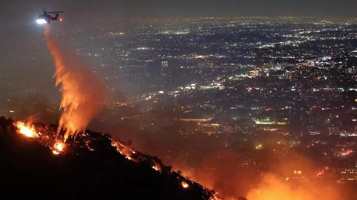 Trực thăng chữa cháy phun nước xuống đám cháy ở Hollywood Hills, Los Angeles, California năm 2025. ẢNH: Getty Images