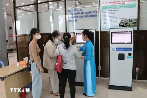 Nhân viên Bệnh viện Đa khoa Tiền Giang, tỉnh Đồng Tháp hướng dẫn người bệnh làm thủ tục đăng ký khám bệnh trực tuyến. (Ảnh: Hữu Chí/TTXVN)