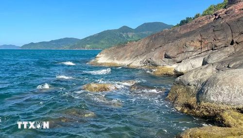 Những hòn đá xám sẫm nằm rải rác dưới chân núi Hải Vân, như những mảnh ghép thô ráp của thiên nhiên xen lẫn giữa vẻ đẹp dịu dàng của biển xanh Lăng Cô. (Ảnh: Văn Dũng/TTXVN)