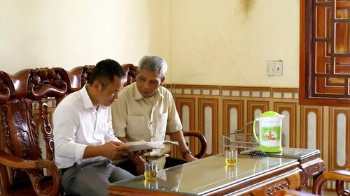 Thầy giáo Hồ Quang Tuyến (áo trắng) gặp gỡ các già làng, trưởng bản để hoàn thiện tài liệu chữ viết Bru-Vân Kiều- Ảnh: A.T