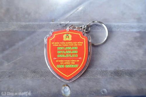Công an xã Lương Tâm tặng móc khóa ANTT có số điện thoại Công an cho người dân.