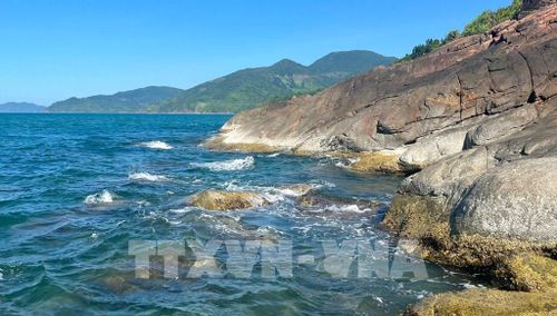 Những hòn đá xám sẫm nằm rải rác dưới chân núi Hải Vân, như những mảnh ghép thô ráp của thiên nhiên xen lẫn giữa vẻ đẹp dịu dàng của biển xanh Lăng Cô. Ảnh: Văn Dũng-TTXVN