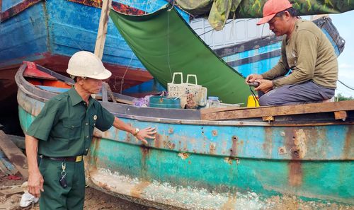 Cựu chiến binh Cao Xuân Đố trực tiếp chỉ đạo công việc sửa chữa tàu thuyền - Ảnh: T.L