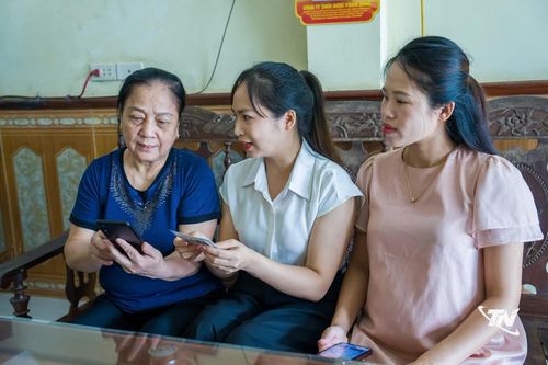 Bà Dương Thị Thiềng (bên trái), tổ dân phố 2, xã Trại Cau, được hướng dẫn sử dụng các tiện ích số trên điện thoại thông minh.