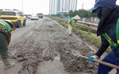 Công nhân môi trường vất vả dọn bùn đất trên Vành đai 3 thuộc địa phận phường Yên Sở. Ảnh: Đức Duy
