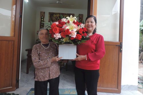 Bà Nguyễn Thị Tình đón nhận hoa chúc mừng từ Ban Công tác Mặt trận thôn Linh Quy khi dọn về nhà mới. Ảnh: VT
