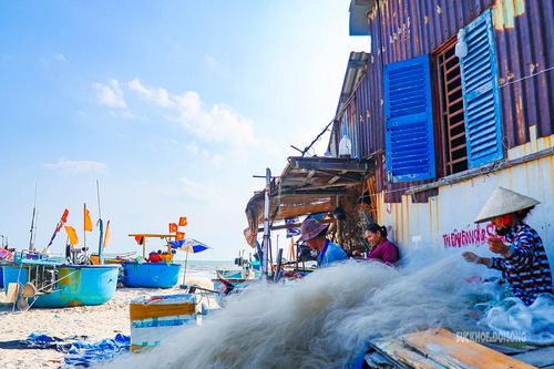 Người dân ngồi vá lưới bên những căn nhà sát mép biển. Ảnh: Lâm Nguyễn