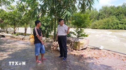 Lãnh đạo Chi nhánh Dầu Tiếng-Phước Hòa (Công ty Trách nhiệm hữu hạn Một thành viên Khai thác thủy lợi Miền Nam) trao đổi với người dân về hoạt động kinh doanh tại hành lang thoát lũ hồ Dầu Tiếng. (Ảnh: Minh Phú/TTXVN)