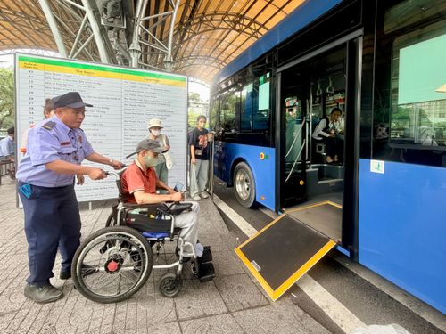Nhân viên bến xe hỗ trợ hành khách sử dụng xe lăn lên xe buýt có sàn nâng tại Bến xe buýt Sài Gòn (Công viên 23 Tháng 9)