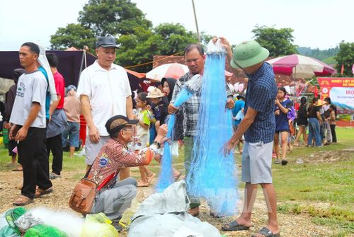 Nhiều đàn ông đang lựa chọn kỹ độ mảnh của sợi đan, kích thước mắt lưới trên từng tấm lưới để mua về phục vụ công việc đánh bắt cá trên sông, suối. Ảnh: Xuân Tiến - TTXVN