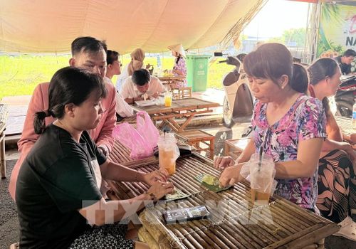 Du khách thích thú thưởng thức bánh rây món bánh truyền thống của đồng bào Khmer An Giang. Ảnh: Thanh Sang- TTXVN