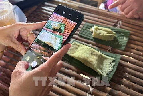 Du khách chụp ảnh lưu niệm những chiếc bánh rây vừa được chế biến tại ngày hội. Ảnh: Thanh Sang- TTXVN