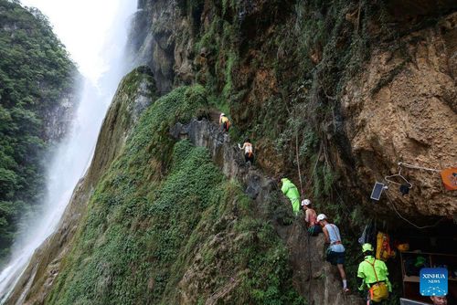 Du khách cùng nhân viên di chuyển đến khu vực trải nghiệm đu dây vượt thác. Những năm gần đây, huyện Hoàng Bình phát triển mô hình du lịch kết hợp thác nước sinh thái, đu dây vượt thác và thưởng thức cà phê giữa núi rừng, từng bước đổi mới các sản phẩm tham quan truyền thống.