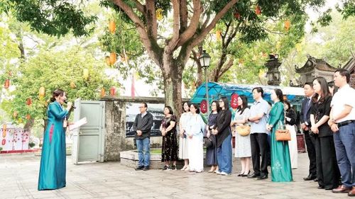 Du khách nghe hướng dẫn viên giới thiệu về Đền Đô (tỉnh Bắc Ninh). (Ảnh: ĐỒNG THÚY)