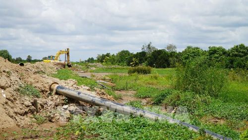 Công trình cao tốc đang thi công khiến nông dân gặp khó về tưới tiêu, không có đường cho máy móc vào đồng ruộng. Ảnh: Nhựt An - TTXVN