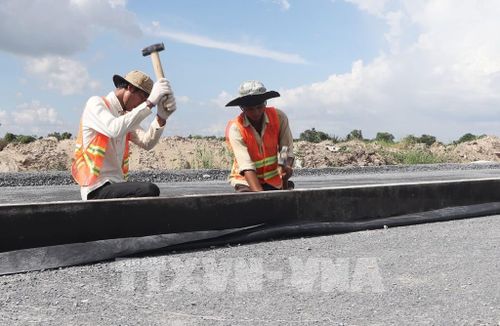 Công nhân đổ bê tông trên đường cất hạ cánh của Dự án mở rộng, nâng cấp Cảng hàng không Cà Mau. Ảnh: Tuấn Phi - TTXVN
