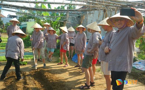 Du khách trải nghiệm làm nông dân tại làng rau Trà Quế. Ảnh: XUÂN SƠN