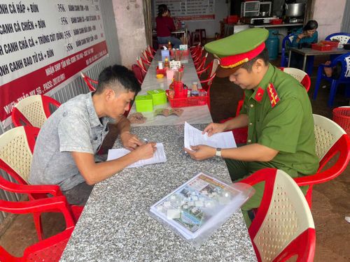 Công an xã KDang (Gia Lai) yêu cầu người dân ký cam kết không tái phạm hành vi lấn chiếm hành lang đường bộ.