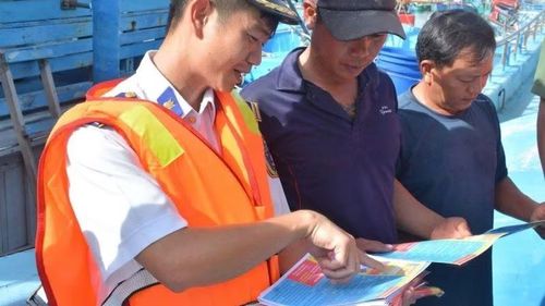 Cán bộ Vùng Cảnh sát biển 3 hướng dẫn ngư dân các nội dung tuyên truyền trên tờ rơi.