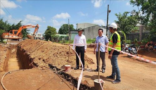 Chủ tịch UBND phường Bình Phước Ngô Hồng Khang (trái) kiểm tra tiến độ Dự án nâng cấp, mở rộng tuyến đường khu phố Tân Xuân 2. Ảnh: Đậu Tất Thành/TTXVN