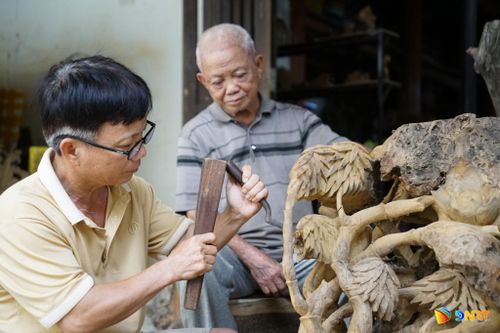 Nghệ nhân nhân dân Huỳnh Ri dõi theo từng đường đục của con trai (Nghệ nhân nhân dân Huỳnh Sướng). Ảnh: TRÂM ANH