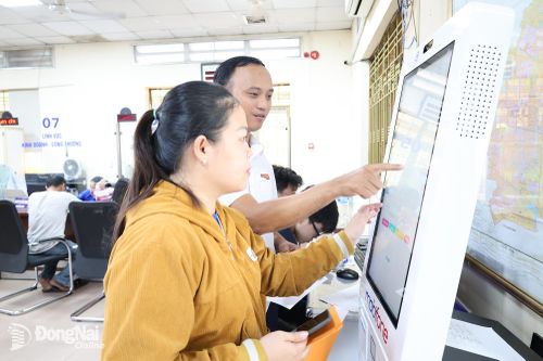 Cán bộ Trung tâm Phục vụ hành chính công phường Trảng Bom hướng dẫn chị Lê Kim Phụng thao tác kê khai thủ tục hành chính trên Kiosk Smart tích hợp AI.