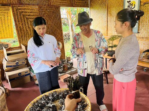 Bà Đỗ Thị Tân Sơn (bên trái) giới thiệu với một du khách trong xưởng trà thủ công của mình