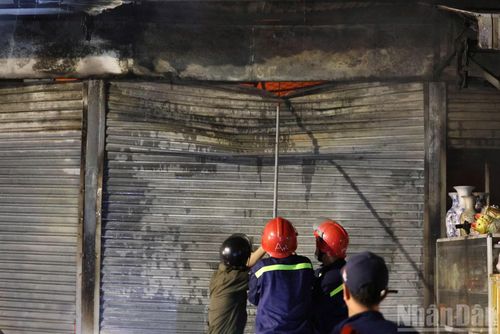 Lực lượng chức năng phá cửa ki-ốt để tiếp cận bên trong dập lửa.