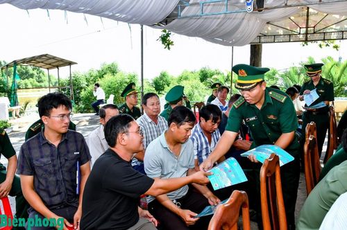 Cán bộ Đồn Biên phòng Trung Bình cấp phát tờ rơi tuyên truyền chống khai thác IUU cho các ngư dân tham dự lễ ra quân. Ảnh: Văn Long