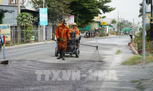 Công nhân tưới nhựa thấm bám, chuẩn bị thảm nhựa Quốc lộ 30, đoạn qua ấp Gò Da, xã Tân Hồng. Ảnh: Nhựt An - TTXVN