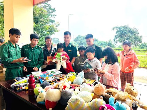 Bộ đội Biên phòng hướng dẫn các em học sinh đọc sách và lựa chọn đồ chơi.
