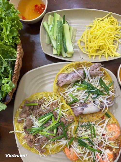 Miếng bánh giòn rụm, vị ngọt của tôm hay mực, độ mềm của thịt bò, vị chua nhẹ của xoài và hương thơm của rau sống hòa quyện tạo nên một tổng thể hài hòa, khiến thực khách ăn mãi mà không thấy ngán. (Nguồn: Vietnam+)