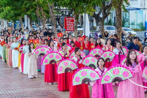 Ngay sau đoàn múa quạt là đoàn diễu hành mặc Áo dài Việt Nam cầm cờ hai nước vẫy chào, thể hiện tình hữu nghị bền chặt. (Ảnh: Thanh Phong/Vietnam+)