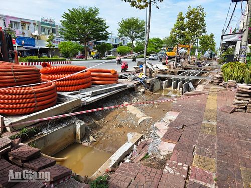 Vật tư ống nhựa và tấm đan được tập kết bên đoạn hào kỹ thuật còn đọng nước trên đường Phan Thị Ràng chờ tái lập mặt bằng. Ảnh: THỤY DU