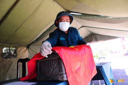 Hài cốt liệt sĩ ở nghĩa trang sau khi khai quật được phủ cờ Tổ quốc. Ảnh: CẨM PHÔ