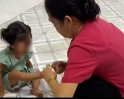 Bảo mẫu dùng giây thun tác động vào chân trẻ. (Ảnh cắt từ clip)