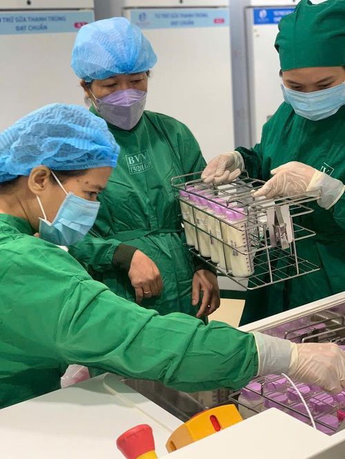 Nhân viên cho các bình sữa vào máy thanh trùng - Ảnh: T.T