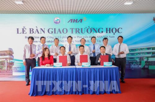 Đại diện các đơn vị thực hiện nghi thức ký kết bàn giao Trường Trung học cơ sở Nguyễn Thái Học và Trường Tiểu học Duy Tân. Ảnh: Giang Phương - TTXVN