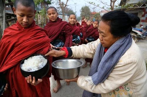 Một nữ phật tử Myanmar cúng dường cơm cho các chú tiểu trong buổi khất thực hằng ngày. (Ảnh: Pascal Mannaerts/Alamy Stock Photo).