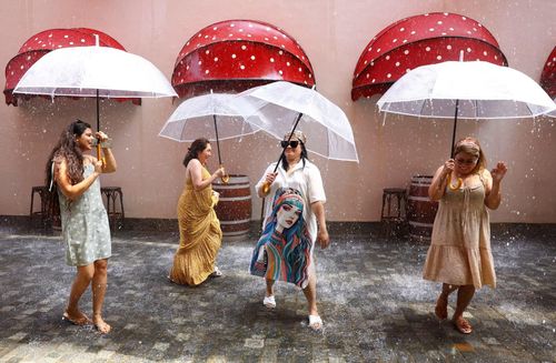 Du khách nhảy múa dưới những chiếc ô trên “phố mưa” được kiểm soát khí hậu tại khu nghỉ dưỡng voco Monaco Dubai, thuộc dự án The Heart of Europe ở Dubai, Các Tiểu vương quốc Arab Thống nhất, ngày 6/8. Điểm tham quan này có thể tạo mưa theo nhu cầu và duy trì nhiệt độ khoảng 27 độ C.