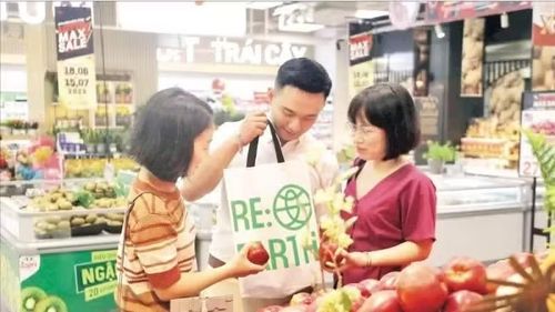Người tiêu dùng sử dụng sản phẩm túi bảo vệ môi trường thay cho túi nylon khi đi mua sắm tại siêu thị. (Ảnh: TÙNG DƯƠNG)