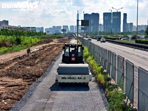 Trên công trường, hàng trăm kỹ sư, công nhân cùng máy móc, thiết bị làm việc liên tục để triển khai các hạng mục mở rộng tuyến đường, trong khi dòng phương tiện vẫn đi lại trên cao tốc TP.HCM - Long Thành.