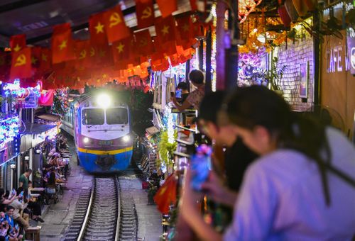 Du khách trong và ngoài nước đồng loạt ghi hình khi đoàn tàu chạy qua phố cà phê đường tàu Hà Nội. Ảnh: Trần Hiền.