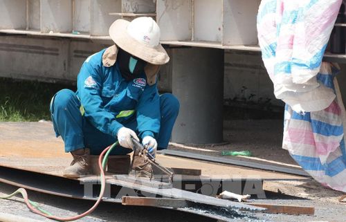 Công nhân trên công trường sửa chữa đập Thảo Long, thành phố Huế, đội thêm mũ rộng vành để giảm tác động nắng nóng. Ảnh: Nguyên Lý - TTXVN
